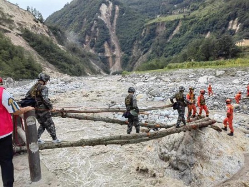 退役軍人志愿者與專業救援隊伍一起進溝開展救援工作，協助消防救援人員搭建救援便橋。四川省退役軍人事務廳供圖