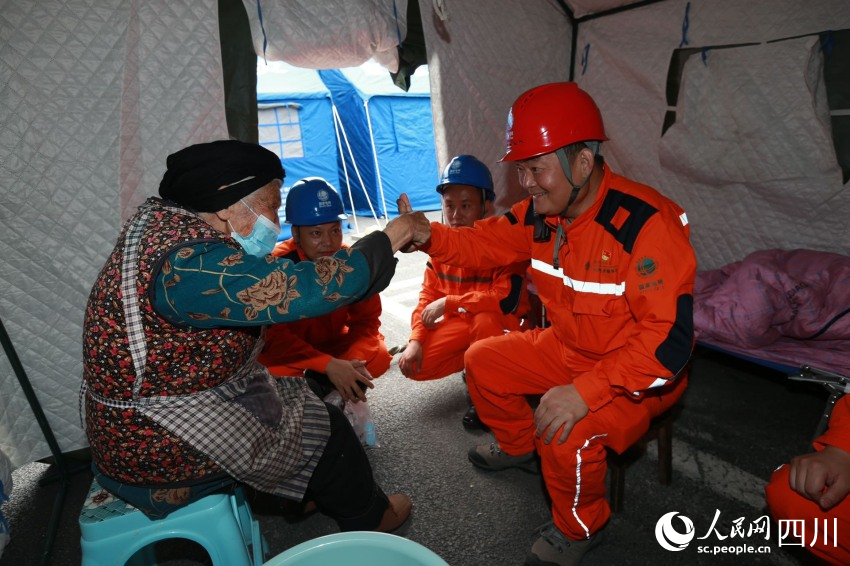 9月6日，國網四川電力（德陽）連心橋共產黨員服務隊隊長魯鵬及隊員們在瀘定縣磨西鎮貢嘎廣場安置點，檢查帳篷中的用電線路，與帳篷中的老人們親切聊天，和小朋友們玩游戲，陪他們度過特殊時光。馬健攝