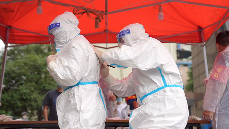 “大白”們相互幫忙穿戴防護服。敘州區融媒體中心供圖