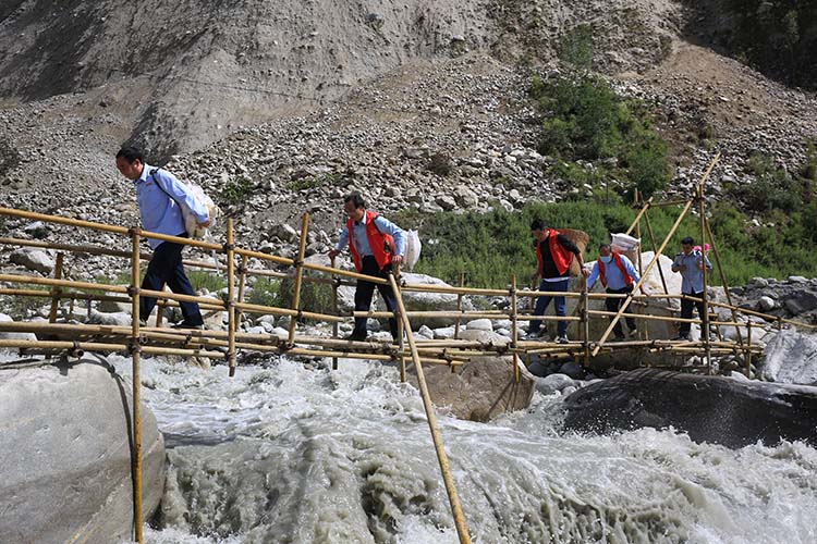 稅務干部背著資料過臨時便橋。四川省稅務局供圖