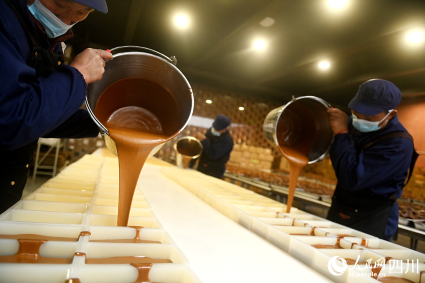 村民們將熬制好的紅糖倒入模具。黃正華攝