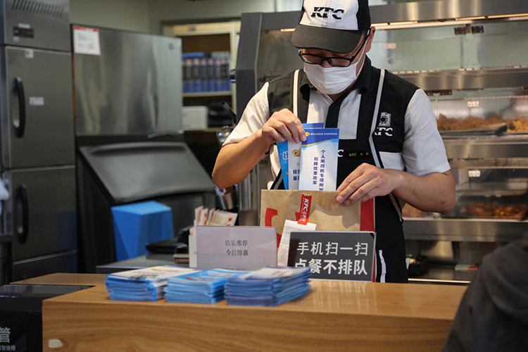 快餐店工作人員將稅法宣傳冊放到快遞盒里面。達州市稅務局供圖