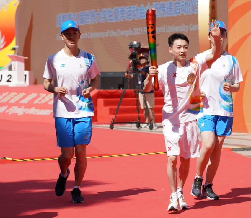 第一棒火炬手、成都體育學院學生、體操奧運冠軍鄒敬園，高舉火炬昂首跑出會場。成都大運會執委會供圖