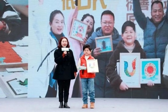 王林江（右）展示團隊做的大運會徽衍紙畫作。成都市殘聯供圖