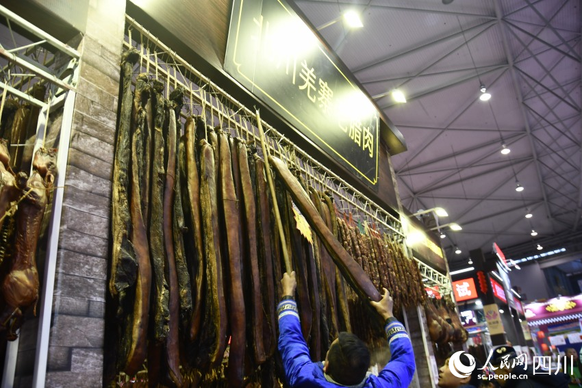 年貨節上，老板正在給顧客取臘肉。人民網記者 王洪江攝