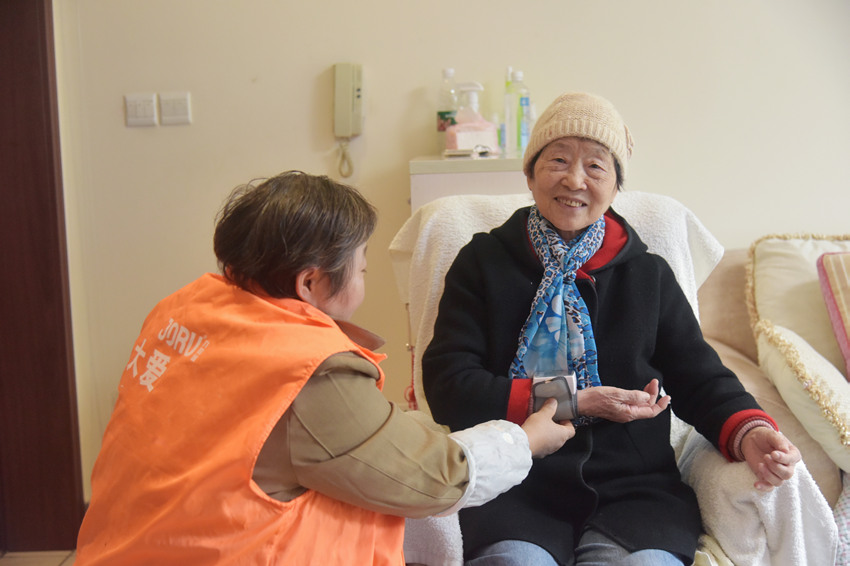 護工“香香”正在給魏秀蘭測血壓。蒲訓訓供圖