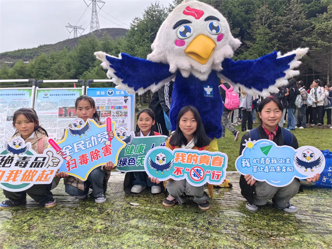 當地學生和涼山禁毒IP“火洛”合影。美姑縣委禁毒辦供圖
