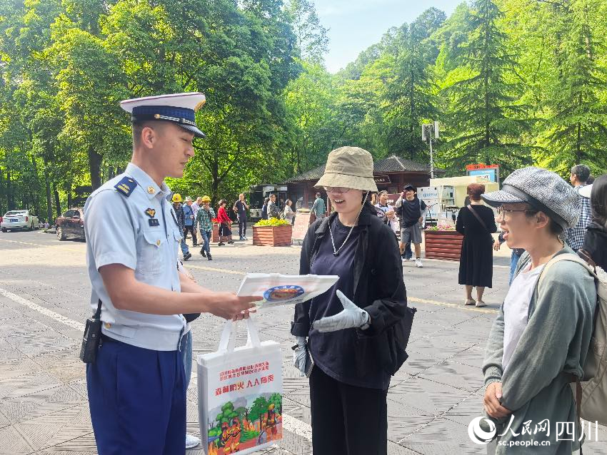 5月1日，青城山門口，消防員裴樂向游客發放防火宣傳單，普及森林防火常識。程雪力攝