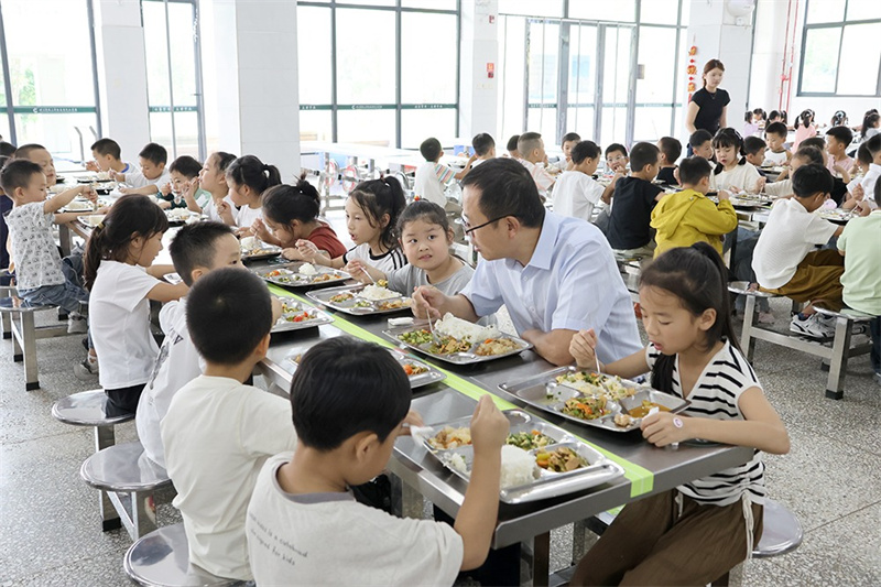 學校校長與孩子們一起吃午餐。綿竹市融媒體中心供圖
