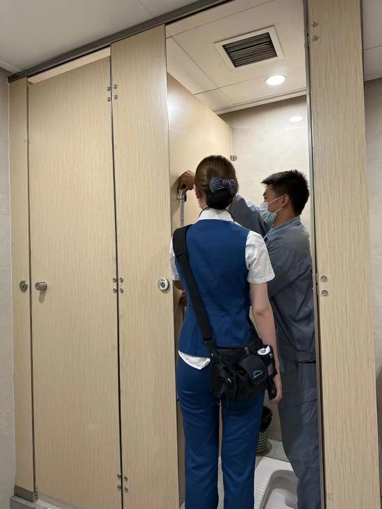 工作人員正在對成都地鐵6號線車站衛生間隔間掛鉤進行測量。受訪者供圖。